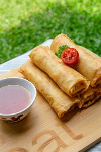 Crispy spring rolls served on a tray with dipping sauce, perfect for a fresh outdoor meal.
